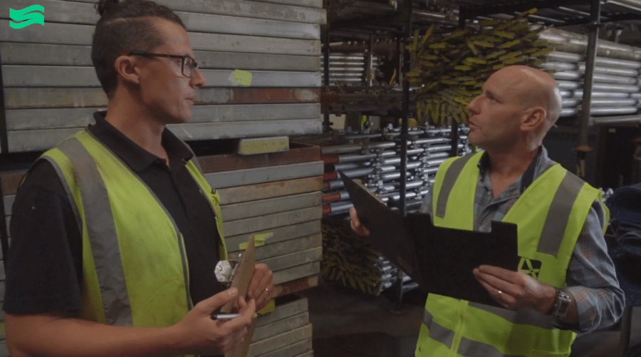 Two men in workshop setting in his vis vests