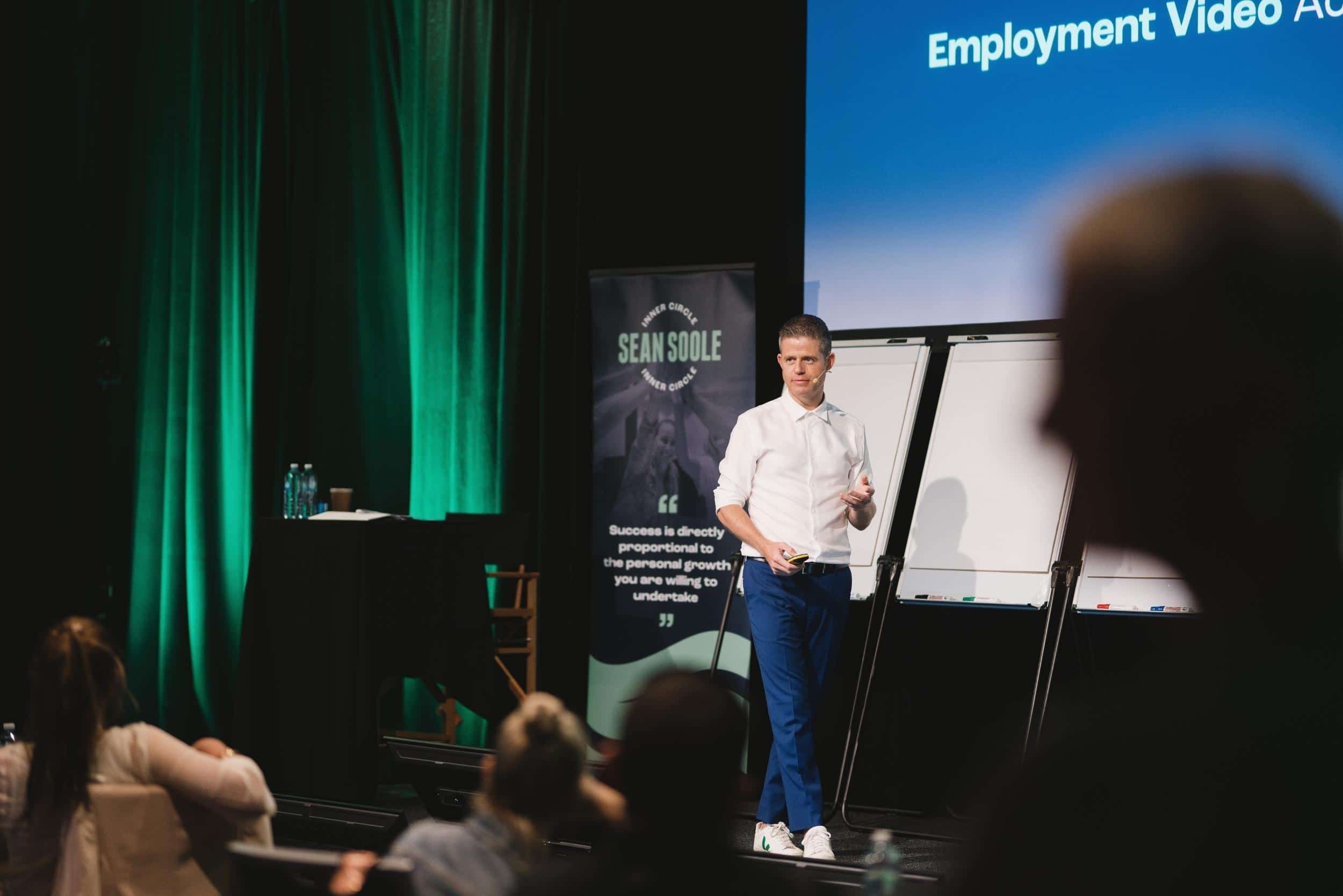 Sean Soole speaking on stage in Noosa